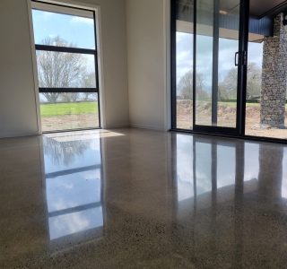 photo of salt and pepper polished concrete floor in lounge area looking towards windows with reflection