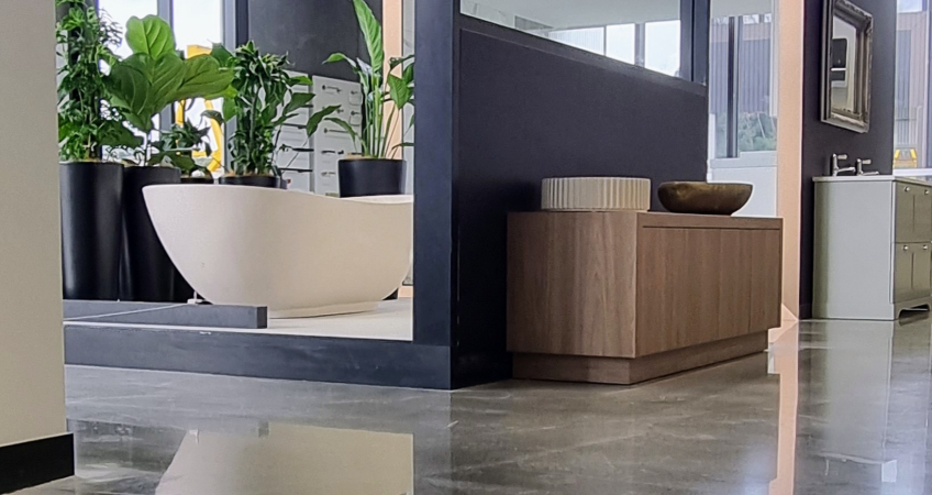 Salt and pepper ground polished floor at Harrison Bloy plumbing showroom showing a bath and vanities in distance