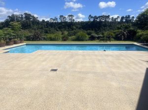 NZ Grinders pool surround non slip bush hammering A pool with concrete tiles around that have been ground back and bush hammered to create a non slip area