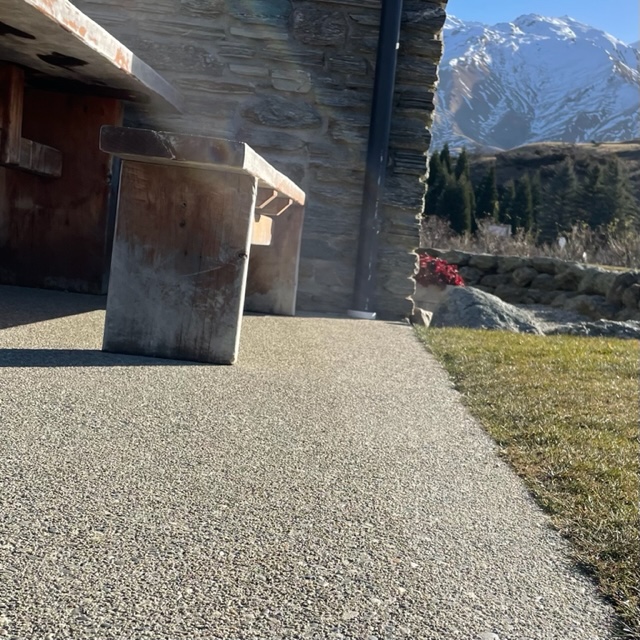 an external patio floor bush hammered for texture with the snow capped mountains in the background and a bench seat in the foreground