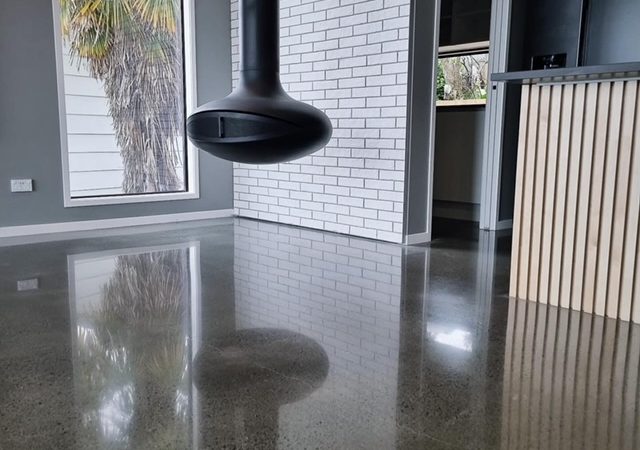 NZ Grinders Tauranga Polished concrete floor in kitchen diner area with hanging fireplace