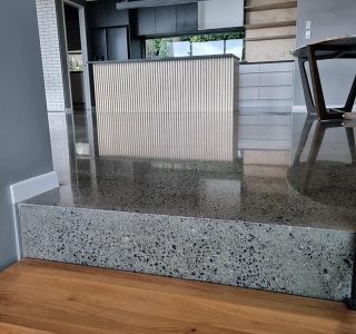 polished concrete step in a house with a kitchen diner in upper area and hardwood floor in lower area