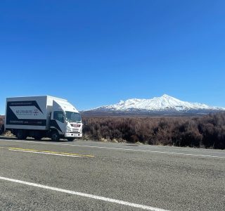 NZ Grinders truck parked at side of road n a clear sky day with a view of Mt Ruapehu in the distance covered in snow