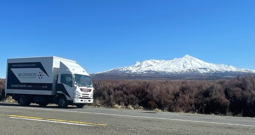 NZ Grinders truck parked at side of road n a clear sky day with a view of Mt Ruapehu in the distance covered in snow